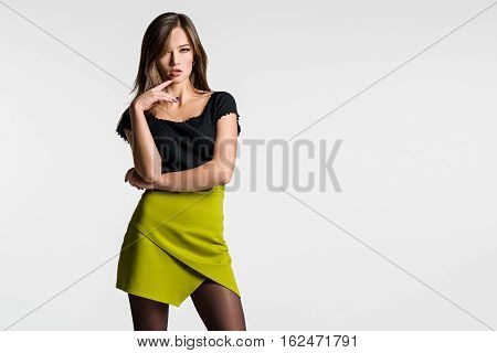 Beautiful woman posing on a light background. The green skirt