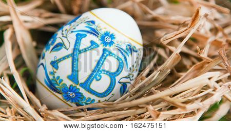 Vibrant holiday background with colorful Russian traditional Easter egg in the dry grass nest with copy space