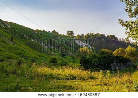 Green chalk hills under a cloudy sky. The multilayered archaeological monument - Krapivinskaya settlement Belgorod region Russia.
