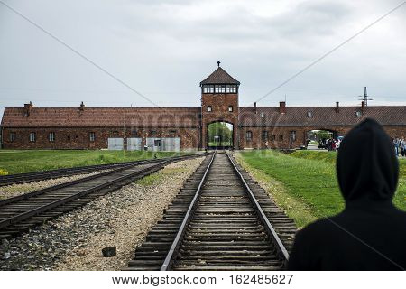 Person standing at Rail entrance to concentration camp at Auschwitz Birkenau KZ Poland