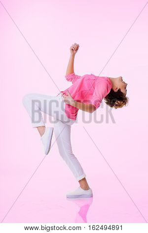 Women in pink shirt dancing in studio. Concept motion. Pink background. Gradient