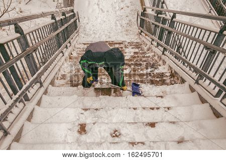 boy shoveling snow from the stairs. child cleans the stairway overpass after snowfall.view from above. the concept of selfless assistance, citizen responsibility