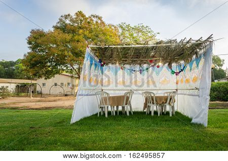 Fabric sukkah decorated with printed pattern and hebrew text of blessing: Grant peace everywhere goodness and blessing Grace lovingkindness and mercy to us and unto all Israel Your people.