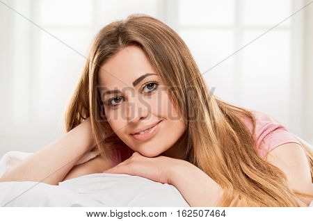 young woman laying in bedroom at early morning, on lightgray window background