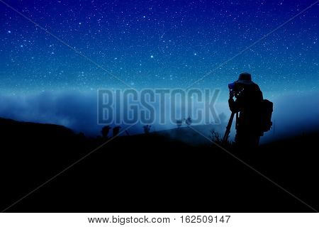silhouette of photographer shooting starry sky at night