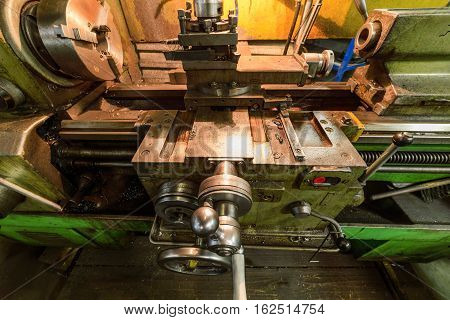 The carriage slide. Mechanical wheel carriage control. Vintage metal cutting lathe. The old mechanical cutting equipment.