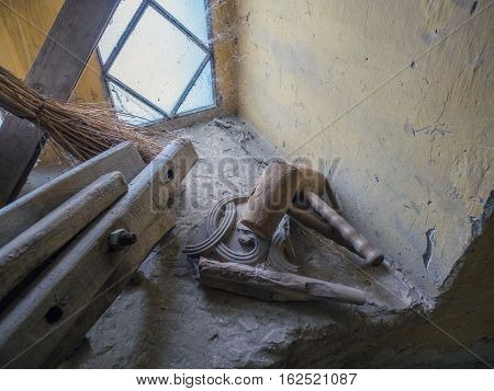 Picture of an old self-made wooden hammer, mallet, close up. Two wooden hammers laying on the yellow windowstool near the broom and wooden planks. A spider web in the coner of the window.