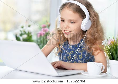cute girl listening to music using headphones and laptop