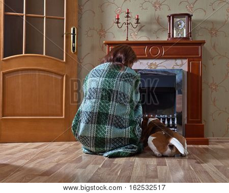 woman in the blanket with dog near a fireplace