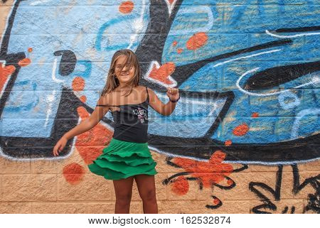 a very beautiful girl who loves posing in front of graffiti