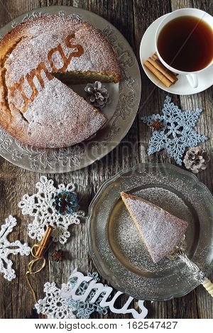 Homemade spiced Christmas sponge cake cup of tea and crocheted snowflakes top view
