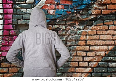 Rear view of hooded man against wall with graffiti