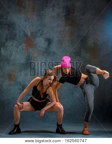 The two attractive girls dancing twerk iat the blue studio background
