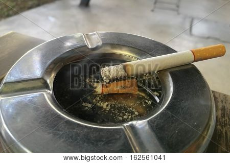 smoking a cigarette, cigarette in ashtray