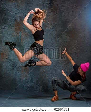 The two attractive girls dancing twerk iat the blue studio background