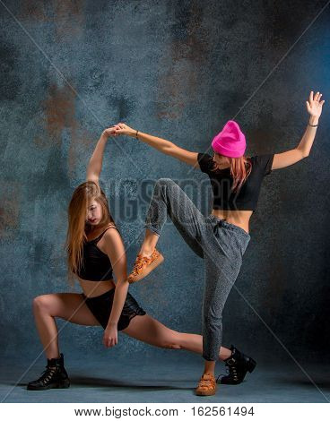 The two attractive girls dancing twerk iat the blue studio background