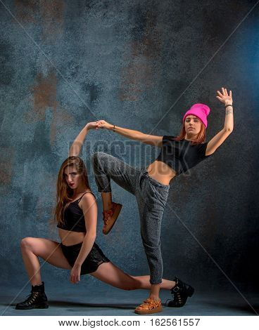 The two attractive girls dancing twerk iat the blue studio background
