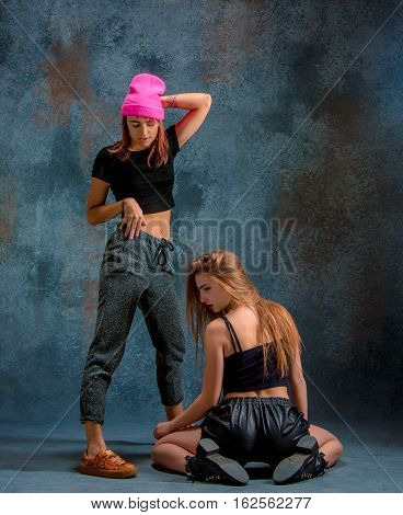 The two attractive girls dancing twerk iat the blue studio background
