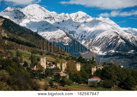 View of the Svanetian towers in Mestia village against mountains with glaciers snow peaks. Upper Svaneti Georgia. Georgian landmark