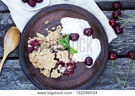 Homemade Cherry crumble wiht ice cream and cherries on an old wooden table background.Selective focus.