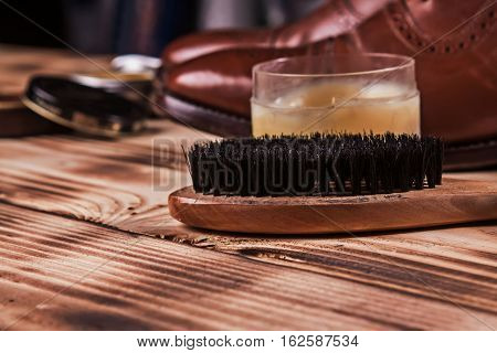 Brush shoes.Shoe care. Shoe wax and brushes on wooden surface.