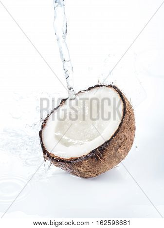 Cracked coconut with water splash isolated on white background