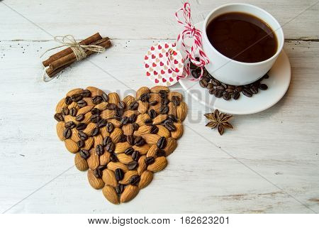 White plate in the form of seashells with coffee beans, cinnamon sticks and star anise, a festive tablecloth and cup with saucer on a dark wooden background.