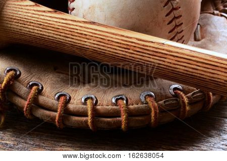 A close up image of an old used baseball glove and bat.