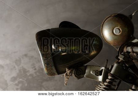 The old bike was parked cement wall left home. Rusty old lamp And bell on the handlebars.