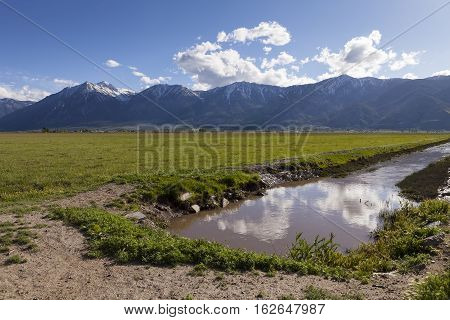 Irrigation Ditch in Carson Valley Nevada with green field and mountains