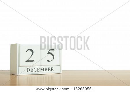 Closeup surface white wooden calendar with black 25 december word on blurred brown wood desk isolated on white background with copy space selective focus at the calendar