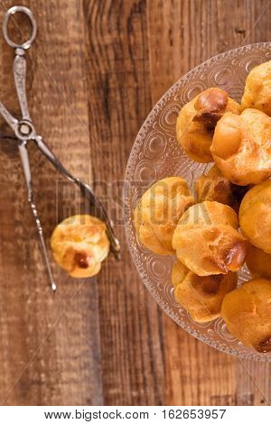 Group of sweet cream puffs on glass tray.