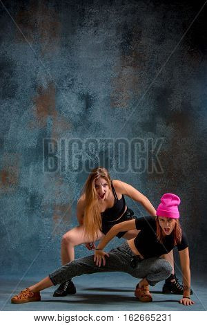 The two attractive girls dancing twerk iat the blue studio background