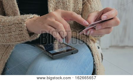 Young woman buying goods from the internet and entering number security code from credit card on smartphone. Online, technology and internet concept