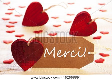 Label With French Text Merci Means Thank You. Many Red Heart. Wooden Rustic Or Vintage Background.