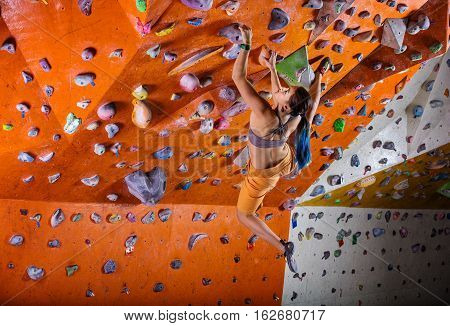 Young beautiful  woman climbing on an artificial wall