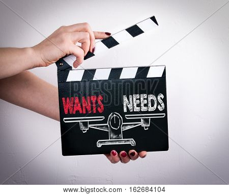 Wants and Needs Balance. Female hands holding movie clapper.