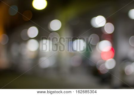De focused/blur image of city at night. A man crossing the road. De focused blurred urban abstract traffic background.
