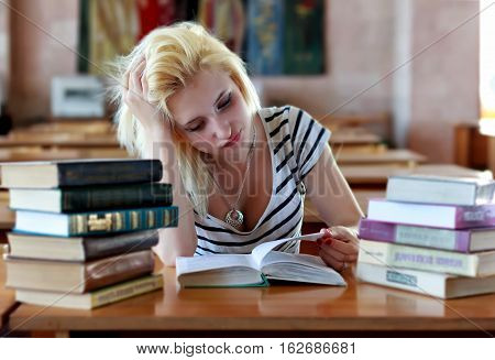 Untidy girl reading a book at a table in the library