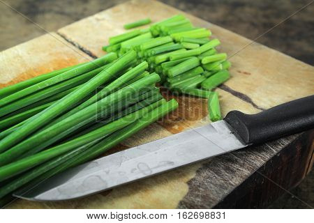 bunch of fresh chives on a wooden cutting board