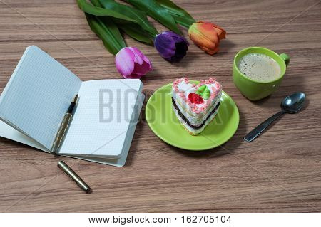green cup of the coffee and a copybook on a wooden table