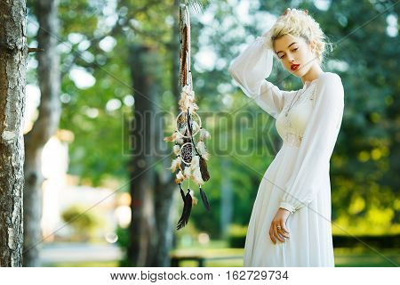 Outdoor portrait of a beautiful model girl with dream catcher vintage and retro tone, soft focus. Full red lips.