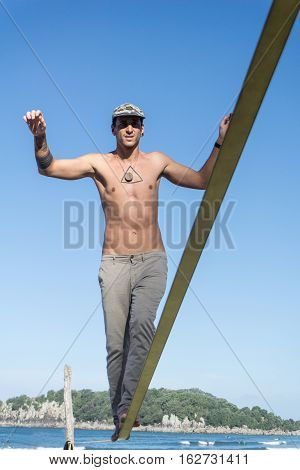 balance and determination focusing on reaching the end slack-line over beach in summer.