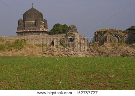 MANDU, MADHYA PRADESH, INDIA - NOVEMBER 18, 2008: Darya Khan's tomb in the hilltop fortress of Mandu. Building with central dome and a smaller dome on each corner in a walled compound. 16th Century AD