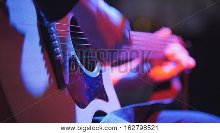 Musician in night club - guitarist plays blues acoustic guitar, extremely close up, telephoto