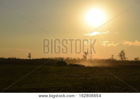 Tractor At Sunset Plow Plow A Field. Tilling The Soil In The Fall After Harvest. The End Of The Seas