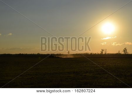 Tractor At Sunset Plow Plow A Field. Tilling The Soil In The Fall After Harvest. The End Of The Seas