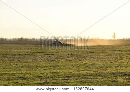 Tractor At Sunset Plow Plow A Field. Tilling The Soil In The Fall After Harvest. The End Of The Seas