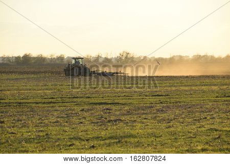 Tractor At Sunset Plow Plow A Field. Tilling The Soil In The Fall After Harvest. The End Of The Seas
