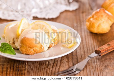 Lemon Profiteroles with lemon fruit on wooden table.